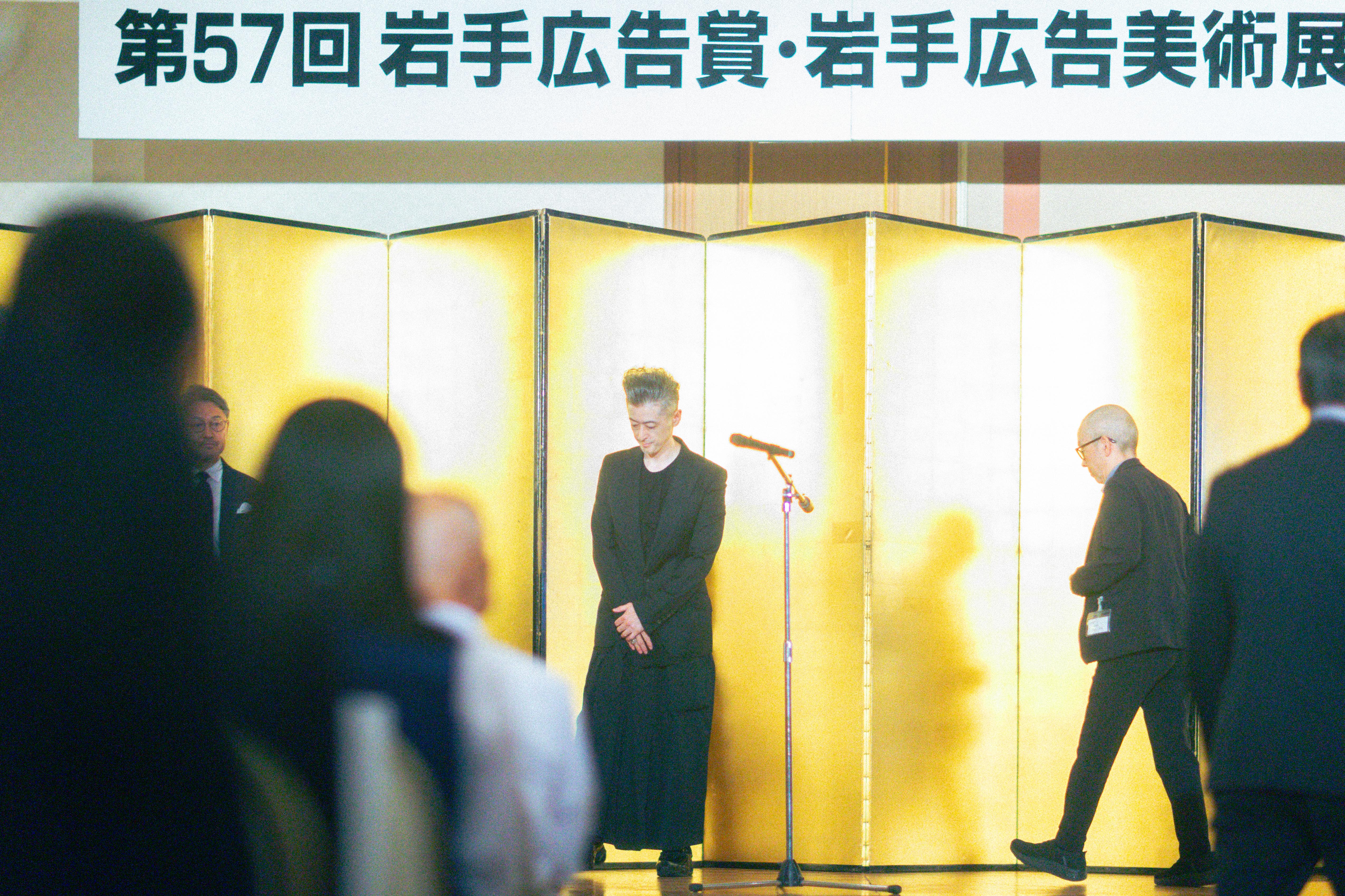 金屏風の前で一礼する中坪久人